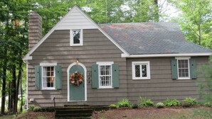 A two-story house with a grey exterior, white trim, and green shutters.
