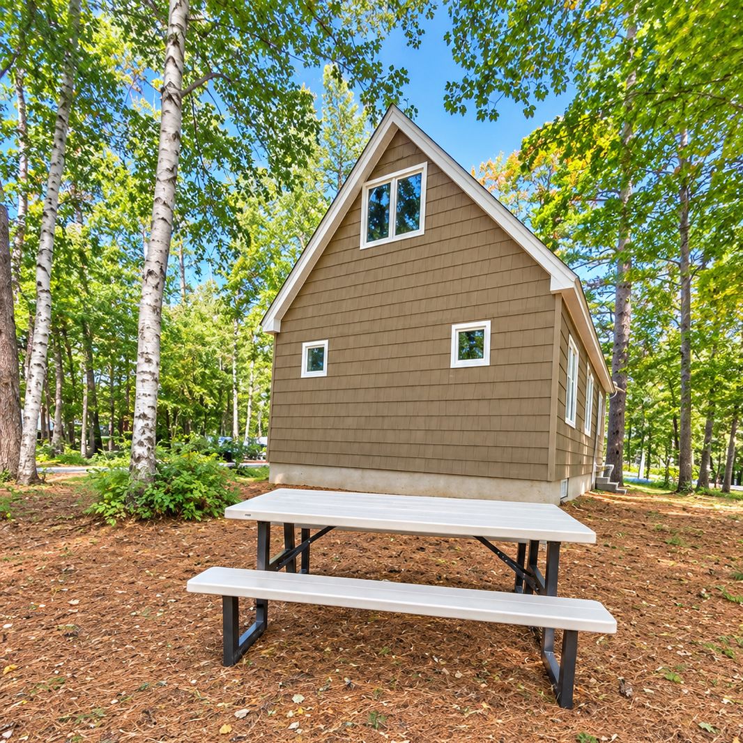 Une petite cabane en bois avec une table de pique-nique, située dans une zone boisée.