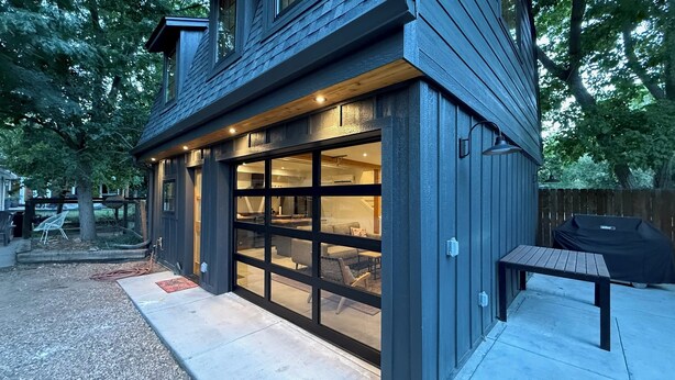 Una casa moderna amb una gran porta corredissa de vidre, un porxo cobert i una barbacoa.