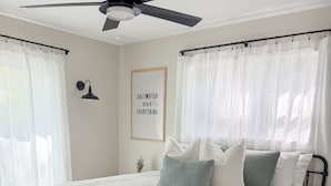 A bedroom with a bed, a ceiling fan, a bedside table, and a bench. - Coastal Getaway • 2bd-2ba • 5 miles to boat ramp and Earl’s hideaway! (Sebastian)