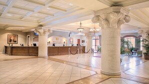 Eine Hotlellobby mit einer Rezeption, Säulen und einem Kronleuchter.