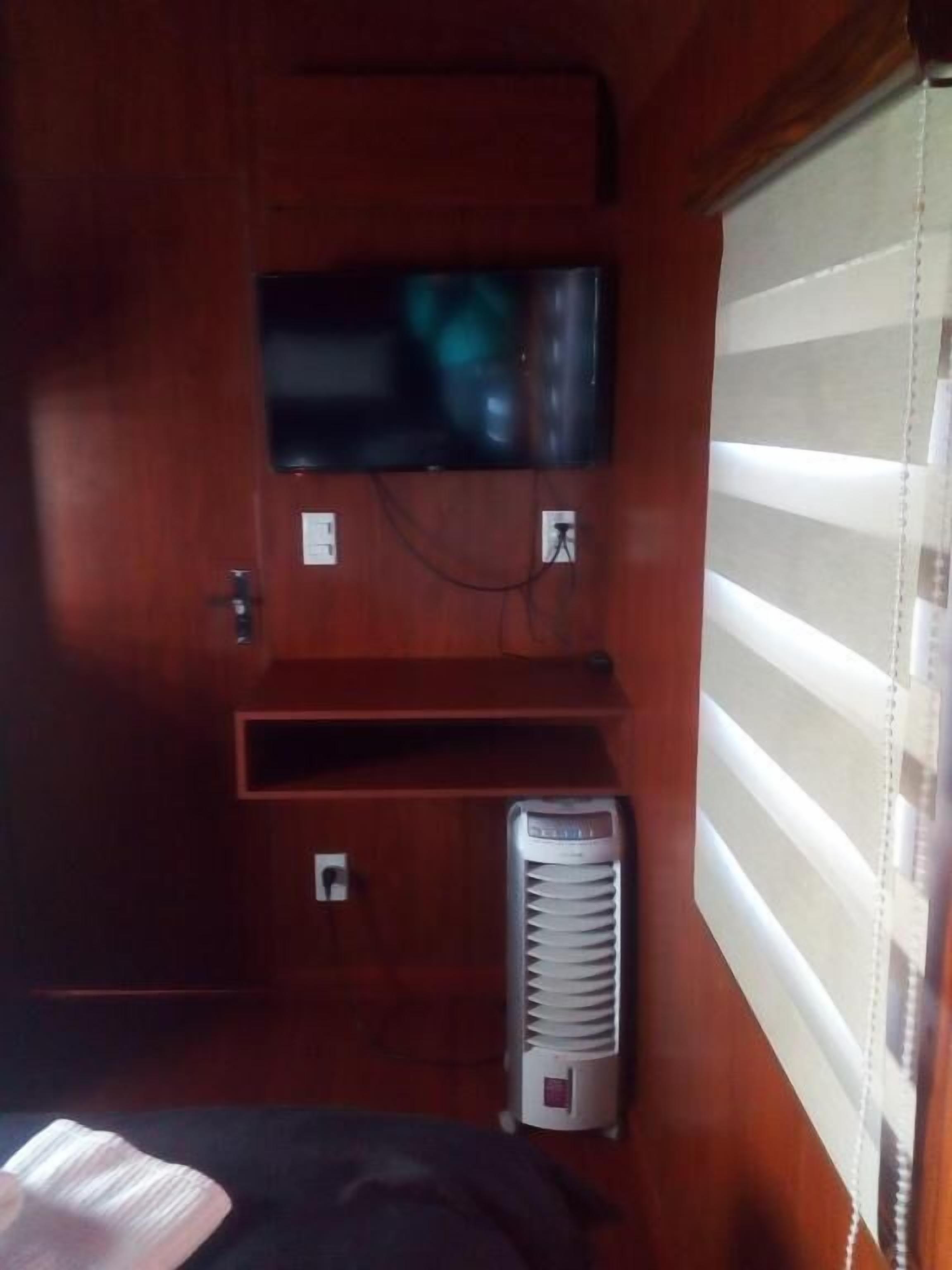 Habitación compacta con televisión de pantalla plana en la pared, calefacción y ventana con persianas.
