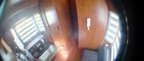 Ein Zimmer mit Holzboden, einem Herd, einem Waschbecken und einem Fenster mit Jalousien.