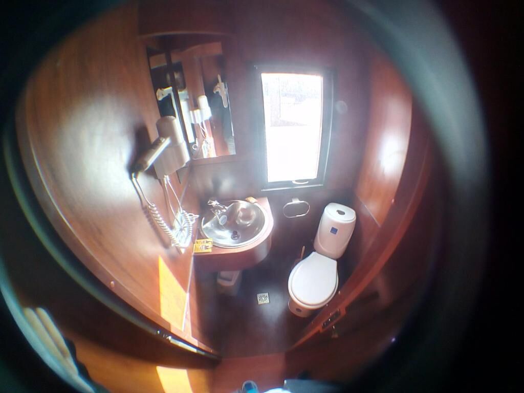 Ein kleines Badezimmer mit Waschbecken, Toilette und einem kleinen Fenster.