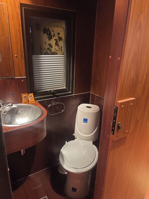 A compact bathroom with a sink, toilet, and window. - Onkel Inn Wagon Sleepbox (Uyuni)