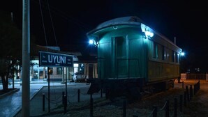 A historic train car displayed at night with a sign reading "UYUNI" in front. - Onkel Inn Wagon Sleepbox (Uyuni)