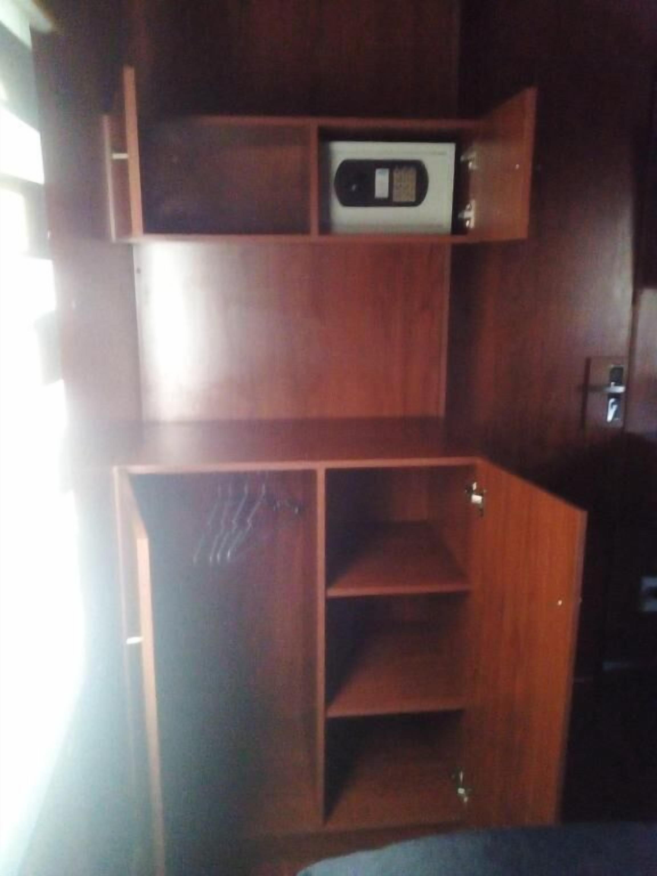 Un mueble de madera con varios compartimentos, incluyendo un estante inferior y un compartimento superior que contiene un pequeño dispositivo electrónico.