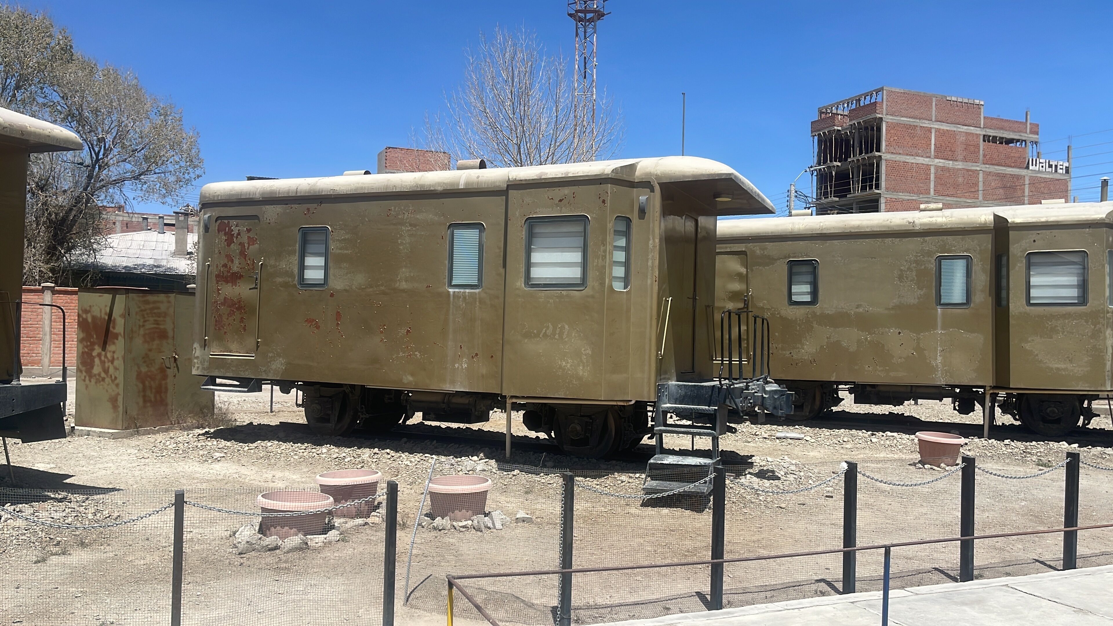 A vintage train car with a metal frame, a small window, and a door.