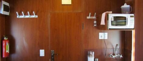 Una cocina compacta equipada con microondas, lavabo y extintor.