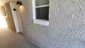 A textured stucco exterior wall with a window and a door. - Luxury Apartment Unit 8 (El Paso)