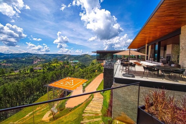 Una terraza moderna al aire libre con vistas a un paisaje montañoso, una cubierta de madera y mobiliario exterior.