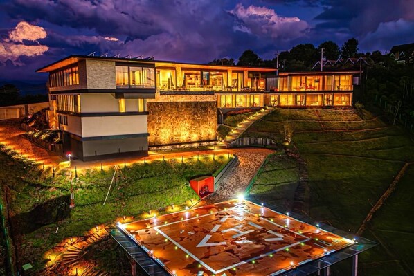 A modern multi-story house with a large deck and outdoor lighting.