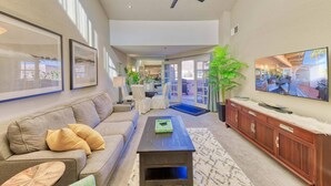 A spacious living room with a sofa, coffee table, and a TV mounted on the wall. - Chic 1-bedroom, 2 baths condo in the heart of Palm Springs. (Palm Springs)