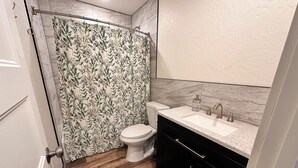 Une salle de bain avec des toilettes, un lavabo et un rideau de douche.