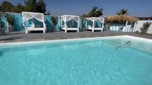 Ein Swimmingpool mit weißen Markisen und Liegestühlen.