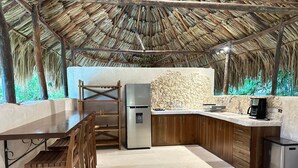 A kitchen with a thatched roof, a stone wall, and a built-in refrigerator. - Casa Yaxunah II 30 min from Chichen (Yaxuna)