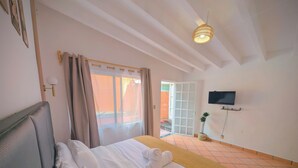 A hotel room with a bed, a television mounted on the wall, and a door leading to a balcony. - Hotel Eterna Primavera Cuernavaca (Cuernavaca)