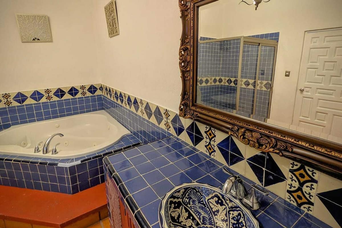 A bathroom with a freestanding bathtub, a large mirror, and patterned tiles.