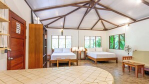 Una habitación con dos camas, una mesa redonda y un ventilador.