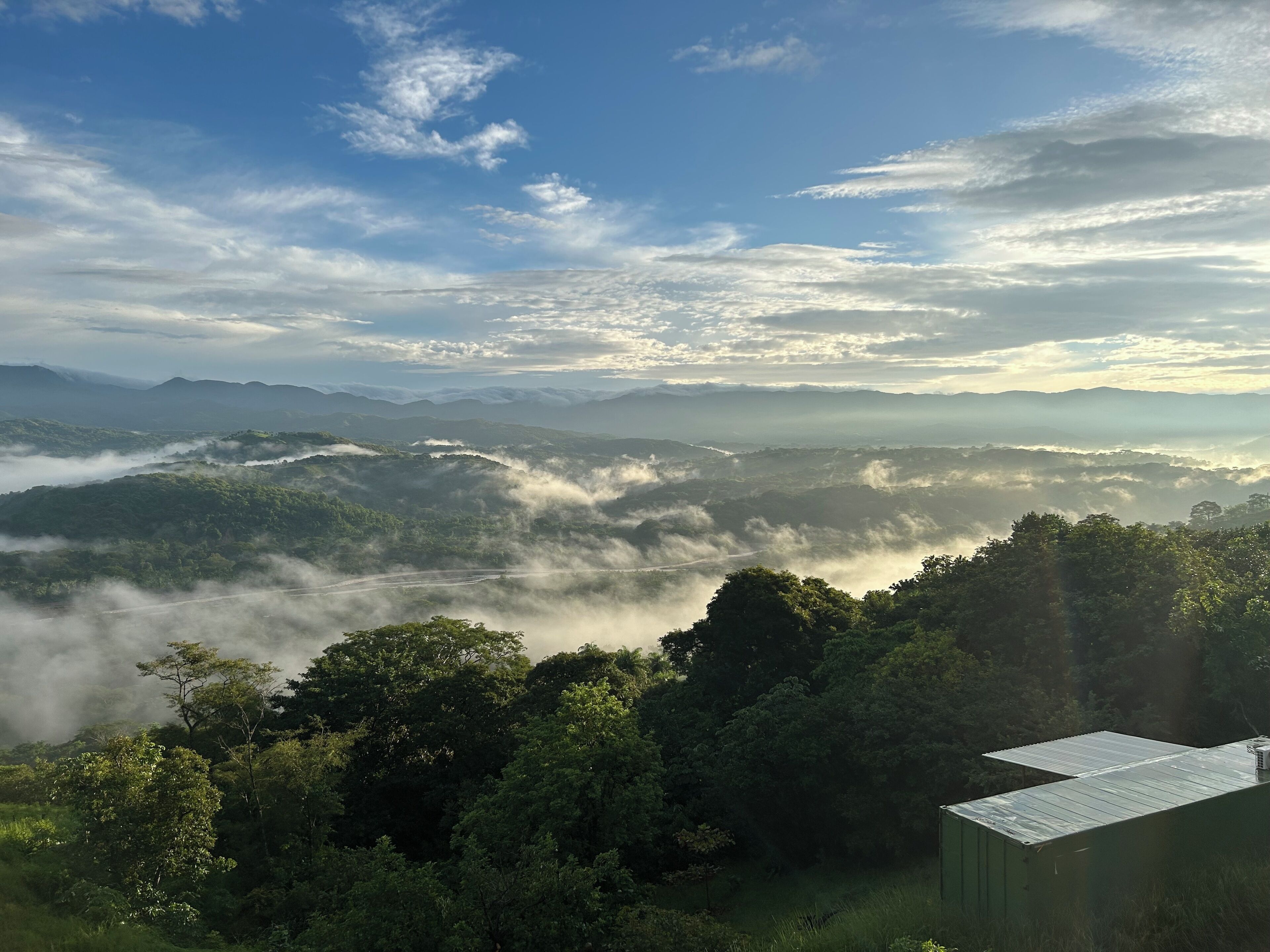 Un paisaje montañoso con un edificio en primer plano.