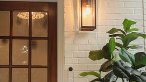 Une porte en bois avec des panneaux de verre et un luminaire fixé au mur.