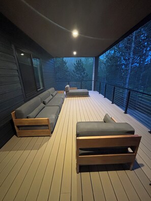 Ein überdachter Außenbereich mit Holzdeck, einer Couch und einer Bank.