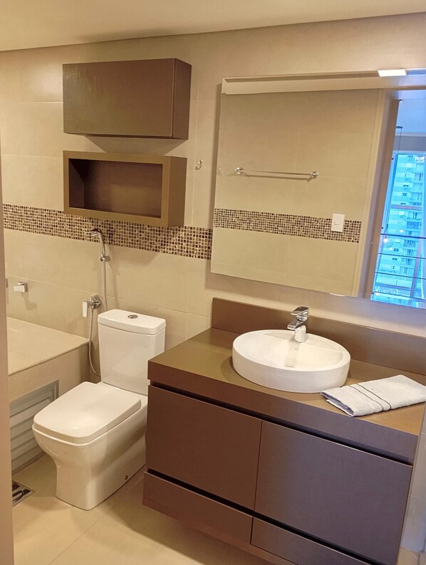 A modern bathroom with a toilet, bidet, sink, and mirror.