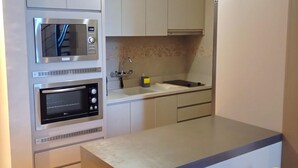Una cocina compacta con electrodomésticos integrados, un lavamanos y un pequeño comedor.