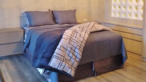 Un dormitorio moderno con cama, mesitas de noche, una araña y decoración en la pared.