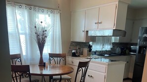 Una cocina con una mesa de comedor, sillas, un refrigerador y un lavamanos.