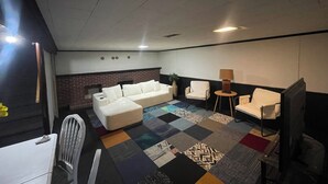 A modern living room with a sectional sofa, a small round table with a lamp, a white armchair, and a TV. - This property is shared with the Host. On the corner in a welcoming neighborhood (Lima)