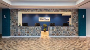 A reception area with a blue wall, patterned tiles, and a herringbone wood floor.