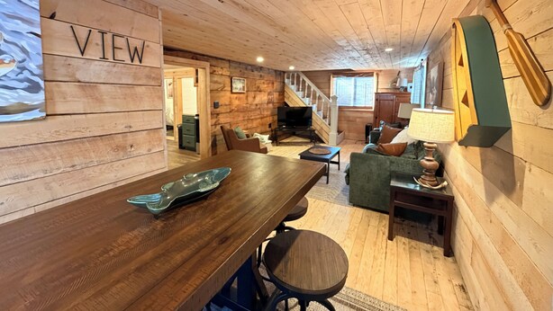 A wooden interior with a dining area, a sofa, and a staircase.