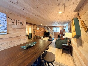 Un interior de madera con comedor, sofá y escalera.
