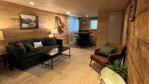 Una habitación acogedora estilo cabaña, con pisos y paredes de madera, que incluye un sofá, una mesita y una silla.