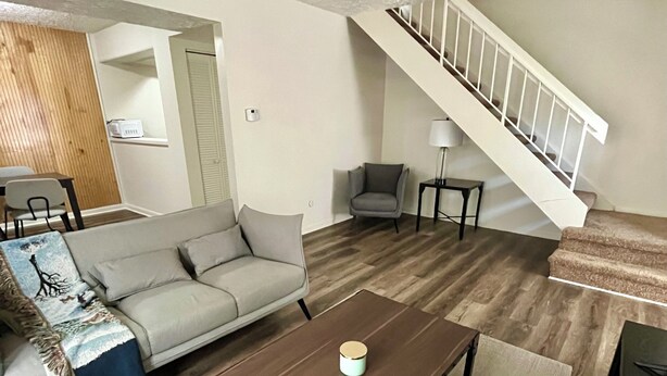 Un salon avec un canapé, une table basse, un fauteuil et un escalier.