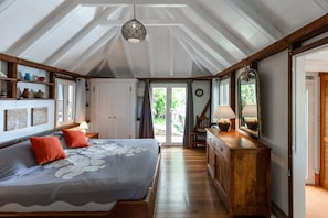 A bedroom with a large bed, wooden dresser, and a ceiling fan.