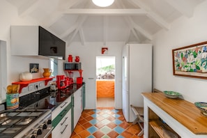 A kitchen with a stove, microwave, and red appliances. There is a window with a view of greenery outside.