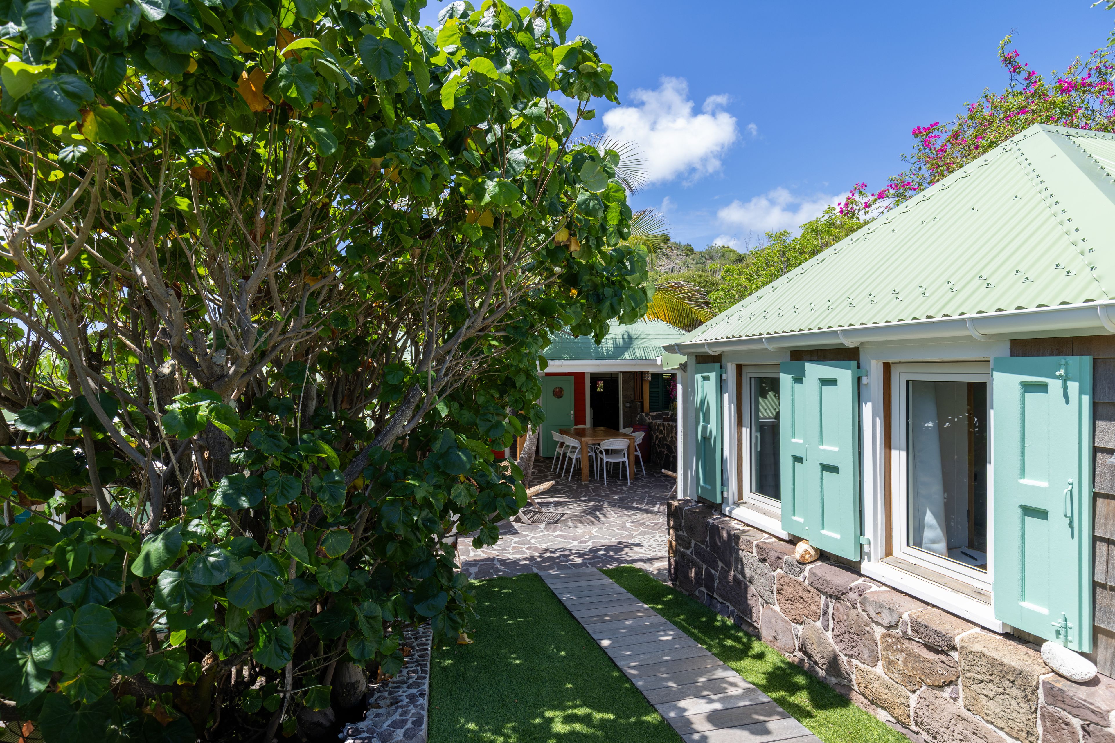 A house with a stone facade, a green lawn, and a dining area with outdoor furniture.