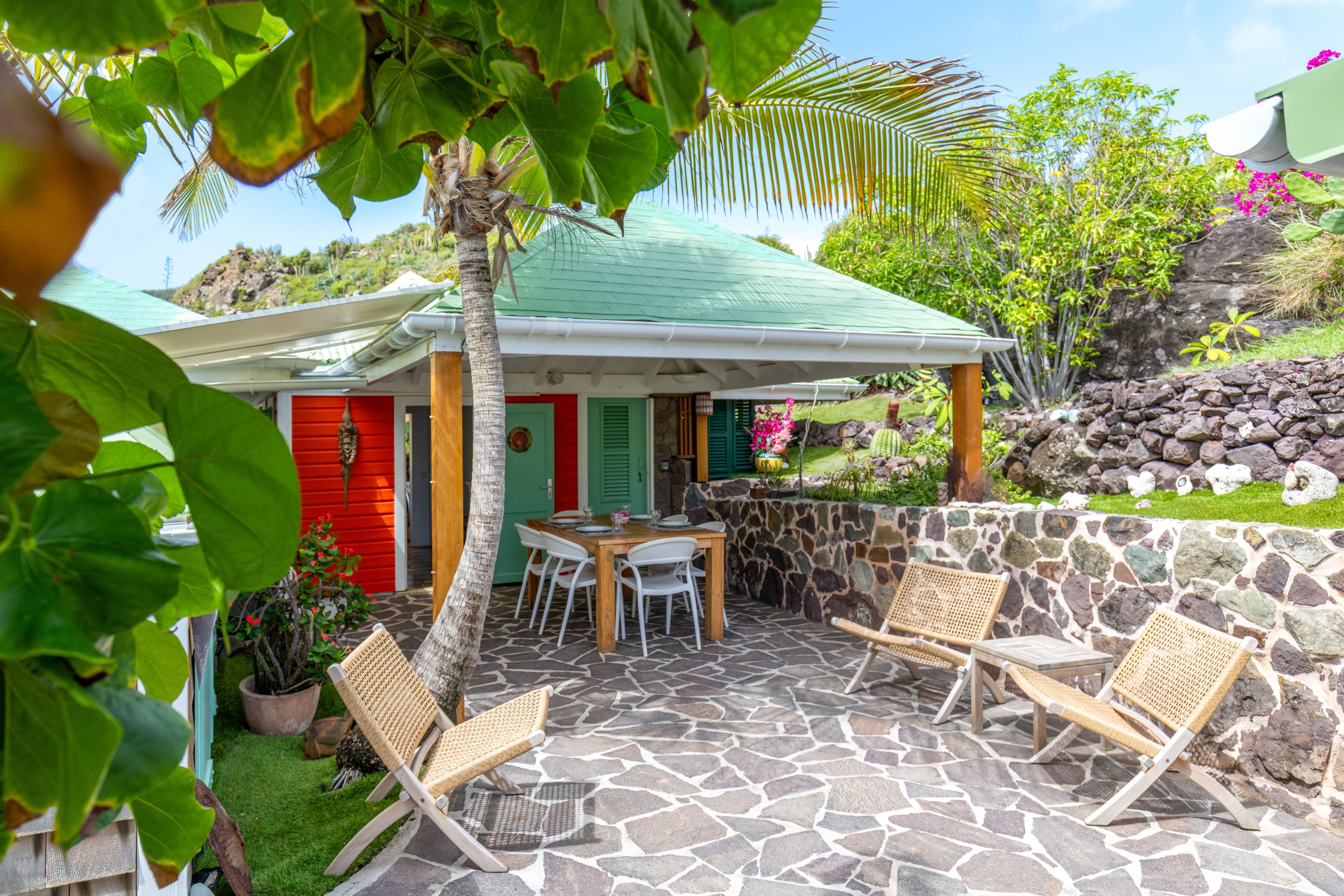 A house with a stone patio, a dining table, and chairs.
