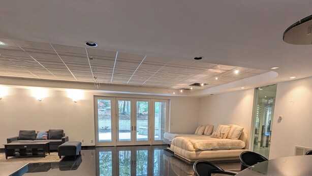 Un salon moderne avec une grande table noire, un canapé et une porte vitrée donnant sur l’extérieur.