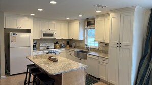 A modern kitchen with white cabinets, a granite countertop, a built-in microwave, a stove, and a sink. - Steps to WEC - Geneva Maison @ Swiss Stables on rare 20 acre estate (Ocala)