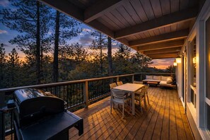 Eine Holzterrasse mit Grill, Tisch und Sofa.