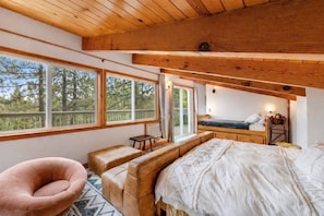 The loft sleeping area features large windows that bring in natural light and peaceful forest views.