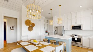 Une cuisine moderne avec des meubles blancs, un îlot central et des luminaires suspendus.