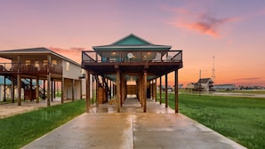 A waterfront property with a covered deck, a staircase, and a view of the water. - Retreat | Gulf Views | Large Deck | Group Ready (Freeport)
