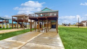 A beachfront property with a covered walkway, multiple decks, and a view of the ocean. - Retreat | Gulf Views | Large Deck | Group Ready (Freeport)
