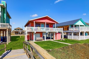 Une propriété située en bord de mer, dotée d’une terrasse en bois, d’un patio couvert et d’un bâtiment à deux étages avec un balcon.
