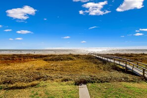 Un sentier côtier menant à la plage, avec un ciel dégagé.