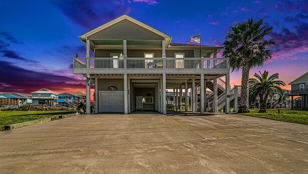 A two-story building with a balcony and a flag. - Retreat | Steps to Beach | Dog Haven | Sleeps 12 (Crystal Beach)